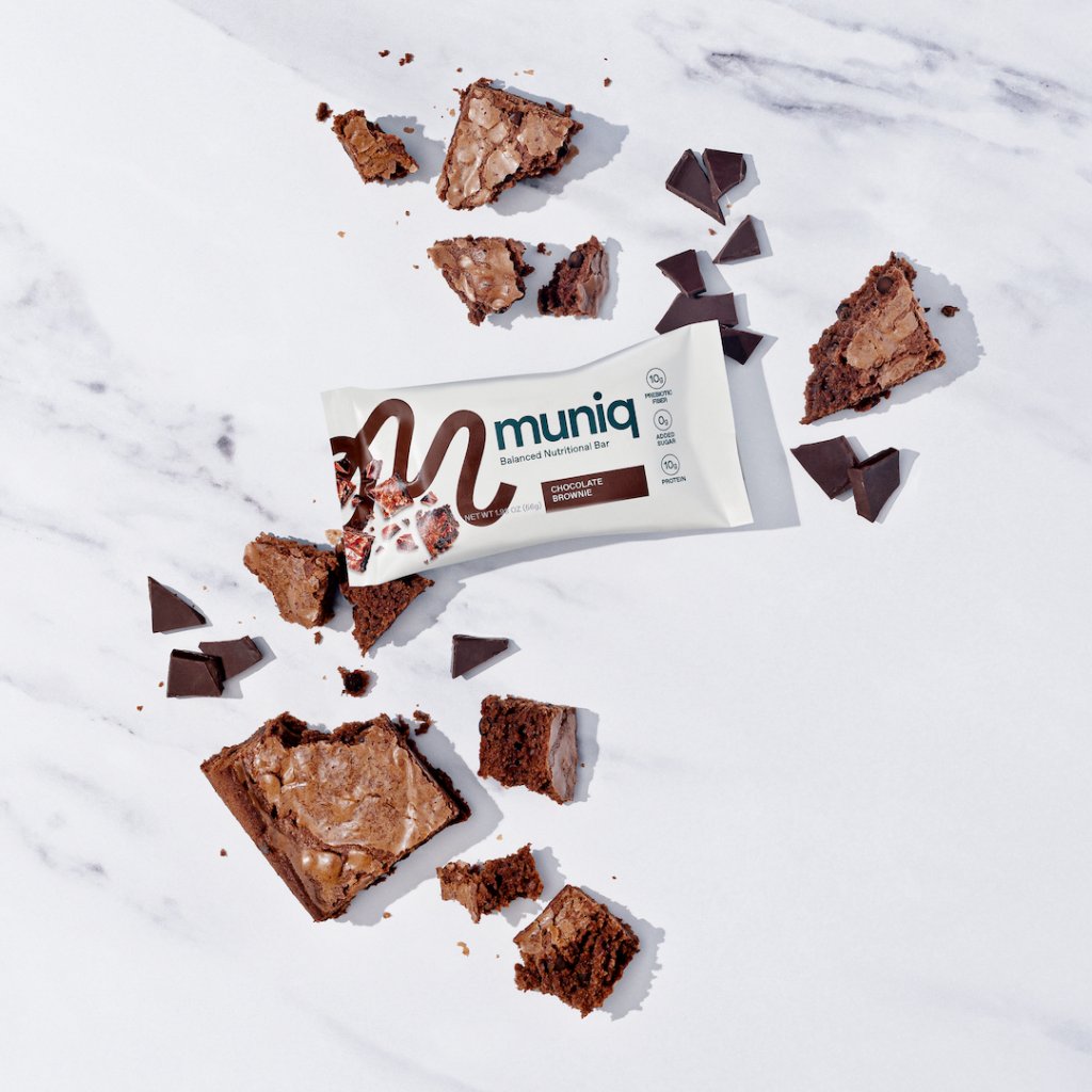 A Muniq bar on a table with bits of chocolate brownie