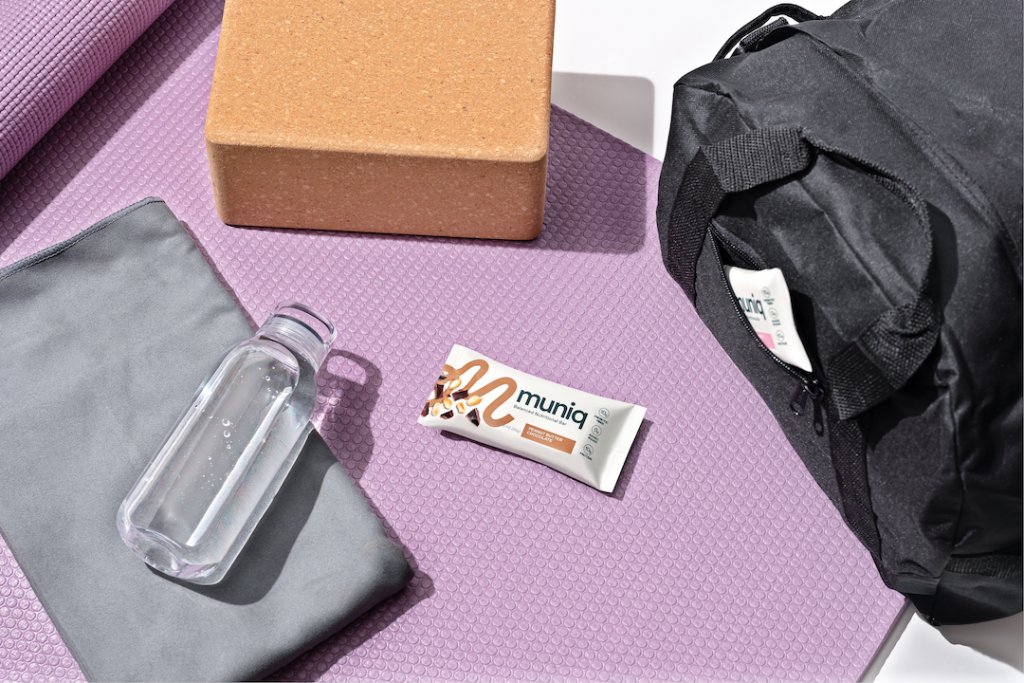 A muniq bar on a yoga mat next to a gym bag